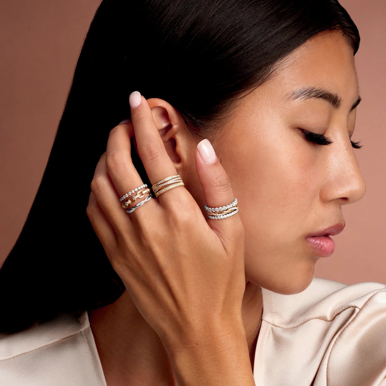 Woman wearing multiple rings on her hand against a neutral background